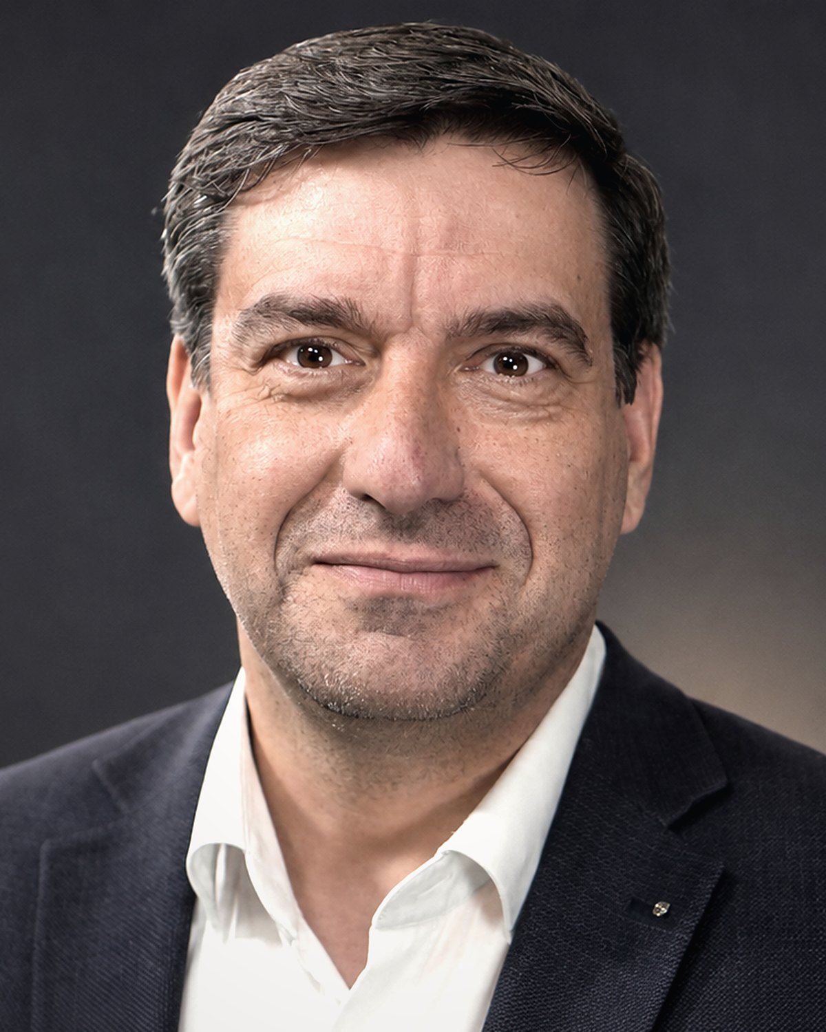 Ralph Kühnl im dunklen Sakko vor dunklem Studiohintergrund